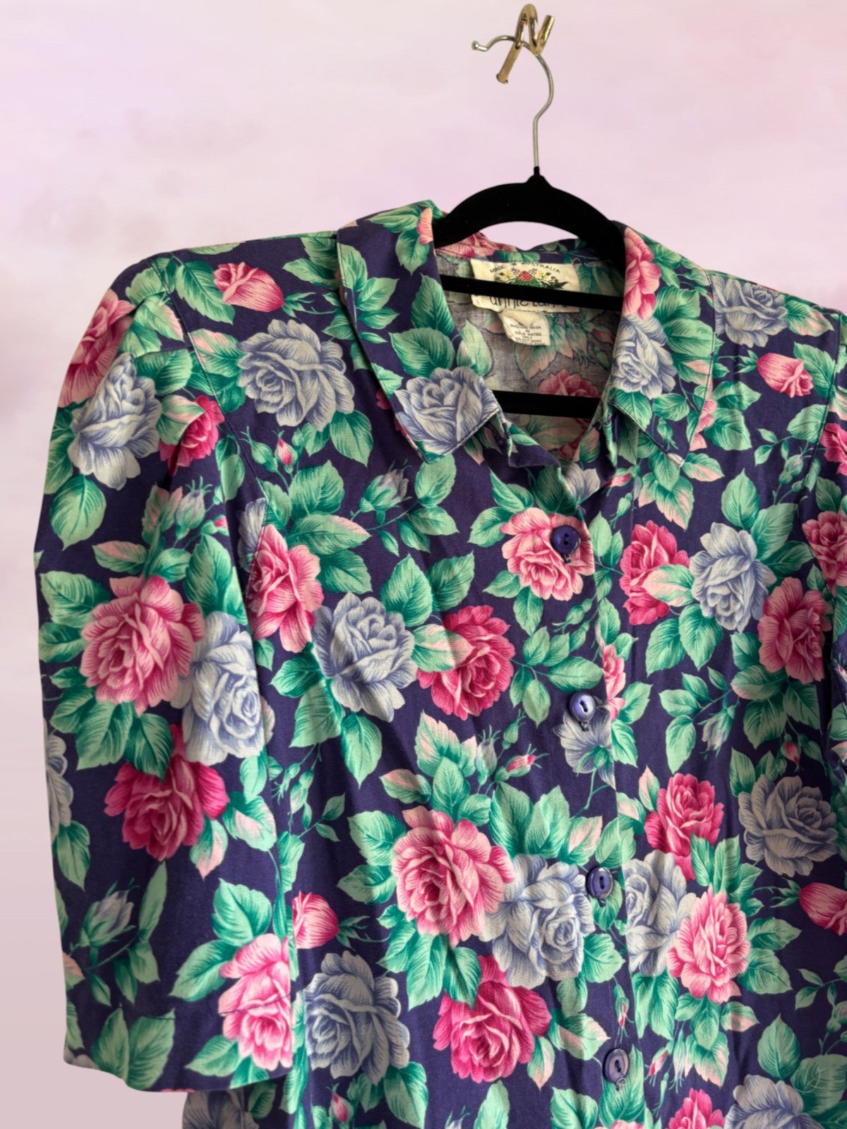 Floral patterned garment on a hanger against a light pink background