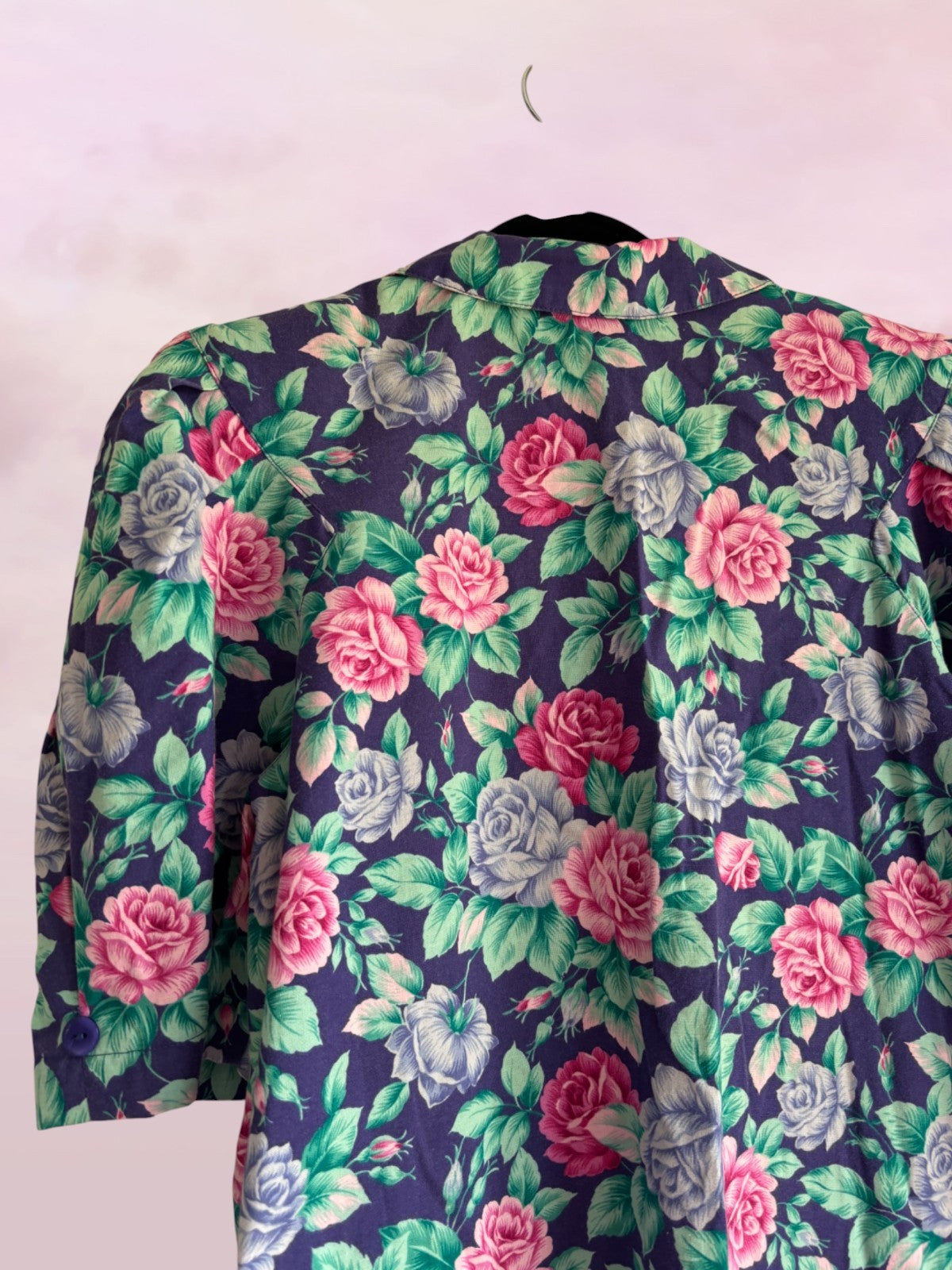Floral patterned garment on a hanger against a white background