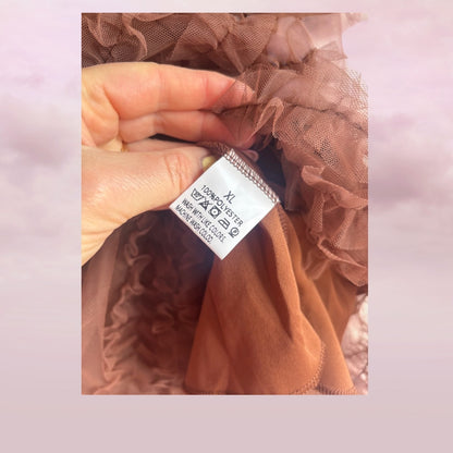Close-up of a sheer brown fabric with a size label on a pink background