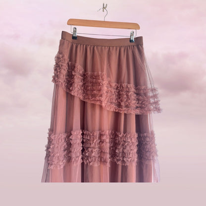 Pink ruffled skirt on a hanger against a pink background