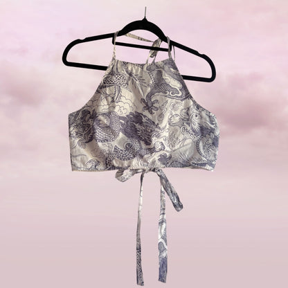 Patterned crop top on a hanger against a pink background