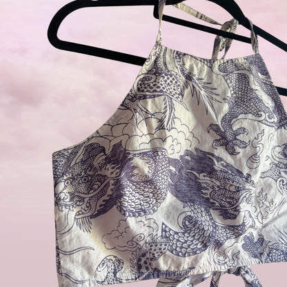 Printed top with fish design on a hanger against a pink background