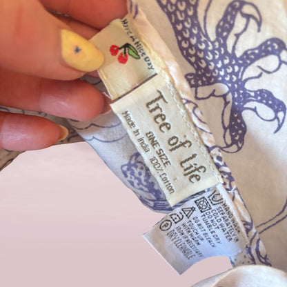 Close-up of a 'Tree of Life' product label held by a hand with a decorative background.