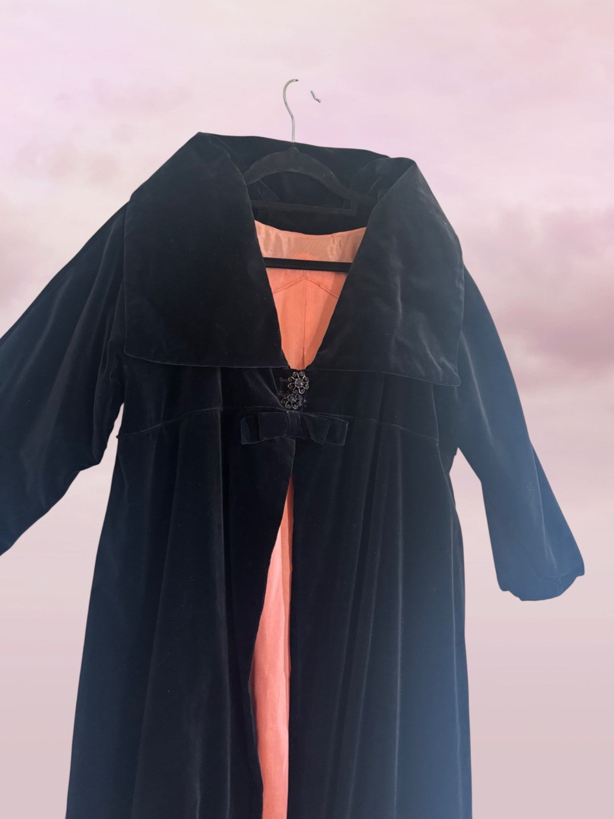 Long dark blue coat with a high slit on a light pink background