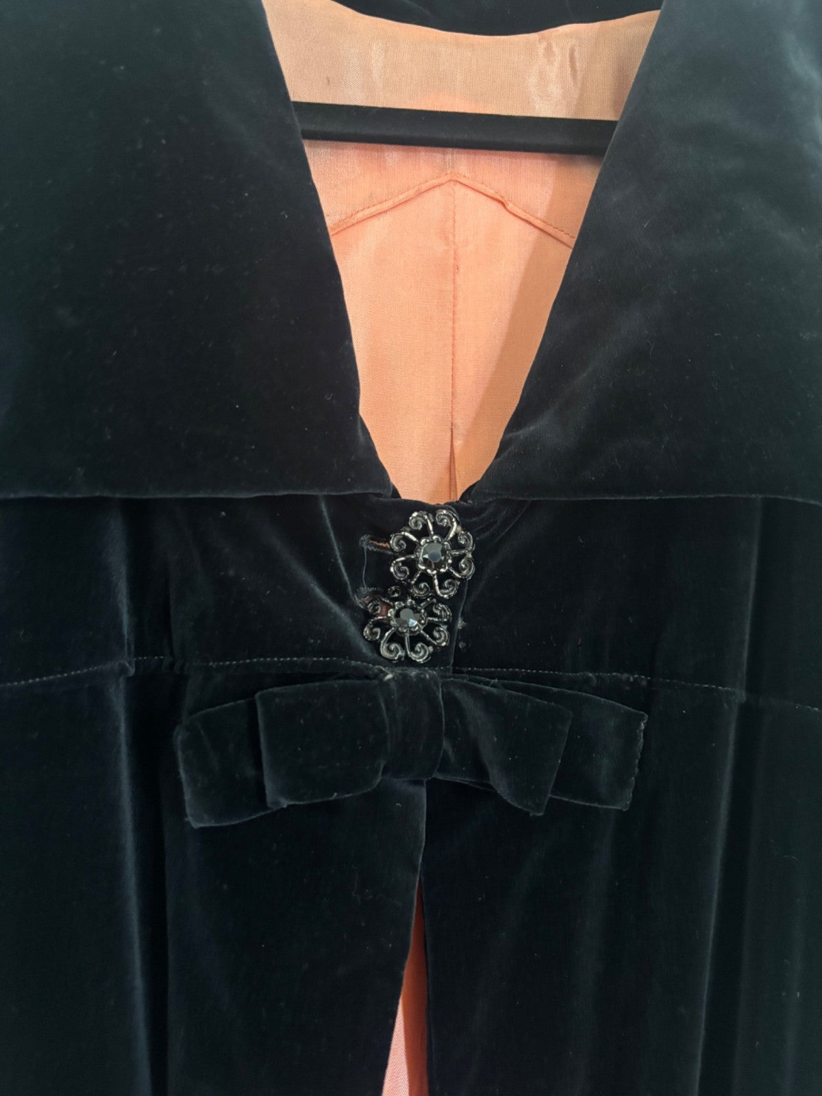 Black velvet garment with a decorative brooch on a plain background