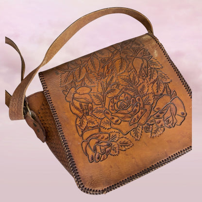 Brown leather bag with floral and hand design on a light pink background