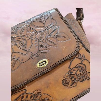 Brown leather bag with floral embossing on a pink background