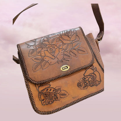Brown leather bag with floral embossing on a light pink background