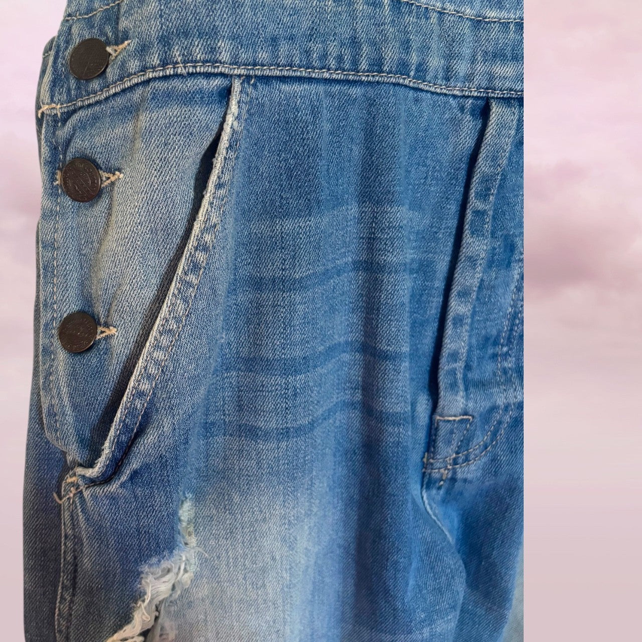 Close-up of a zara blue denim overalls with buttons on a light pink background
