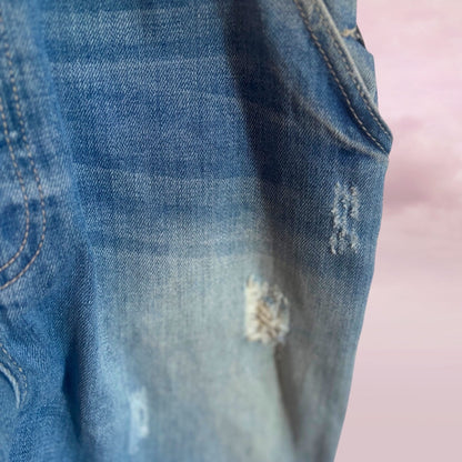 Close-up of Zara blue denim distressed fabric from overalls and pink background
