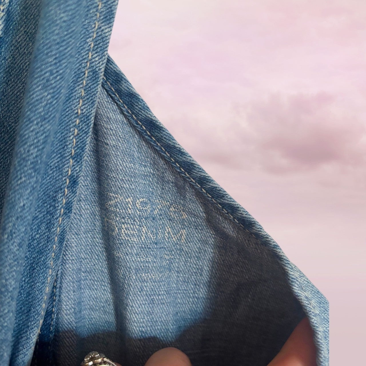 Close-up of zara numbers on overalls blue denim fabric with a brand label on a pink background